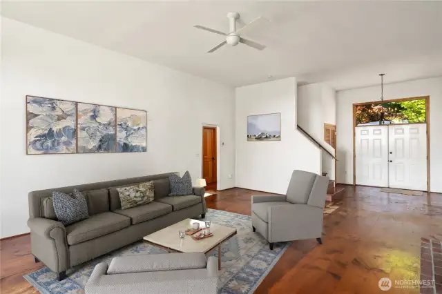 The great room has solid, real wood floors with cut nails, tall ceilings and ceiling fan to keep you cool. The French door in the background is the front door. Note stairs to the upper level lead to two guest bedrooms, a bath and more.