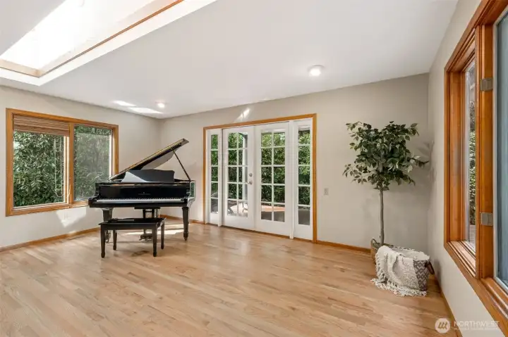 The spacious Family Room is easily split into two uses as seen here as a music room. The beatiful French Doors open out to the covered portion of the back deck. Rich hardwood floors and wood wrapped windows throughout the home.