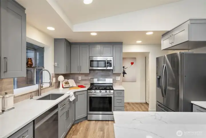 Recently renovated kitchen with stylish painted cabinetry, solid quartz counters, and stainless appliances.