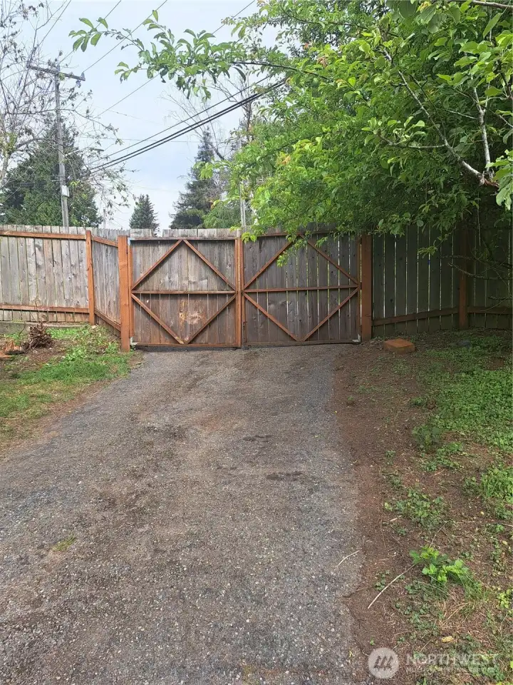 Driveway and driveway gates at north side of property. going down to the single car attached garage and entrance to separate living area.