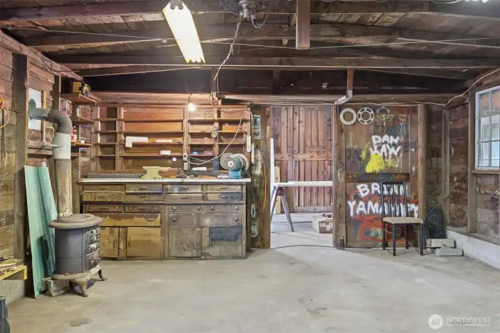 View of one of the interior shop spaces. Work bench and cabinets are built in and ready for your use. Heated by a fire burning heat stove with windows to allow natural light in. View of one of the interior shop spaces. Work bench and cabinets are built in and ready for your use. Heated by a fire burning heat stove with windows to allow natural light in.