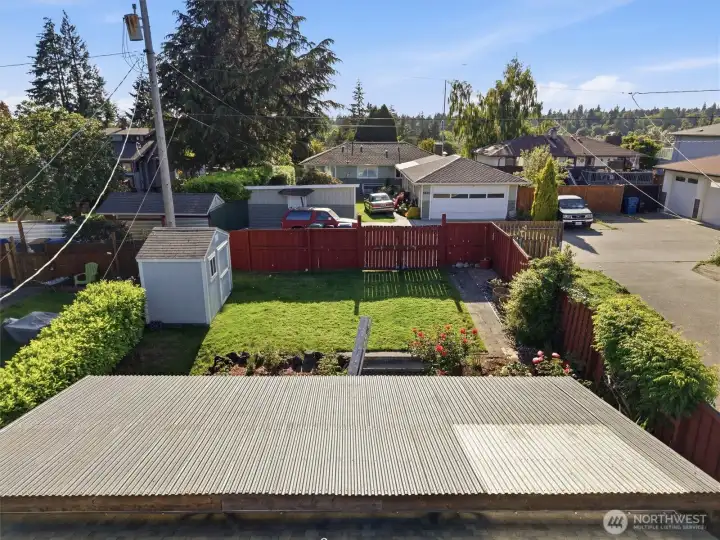 Red fence leads to the paved alley way.