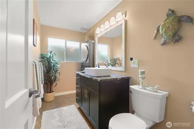 The lower level half bath doubles as the laundry area with the modern stackable washer and dryer unit tucked nicely in the back. Perfect privacy for any guest staying in the lower level bedroom with the Murphy bed.