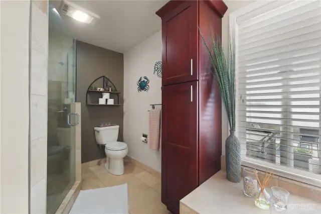 The primary bath is a spa-like haven designed for ultimate relaxation, seamlessly blending luxury with the beauty of its waterfront views. The custom walk in shower features a modern glass door and elegant tile work in calming natural tones.