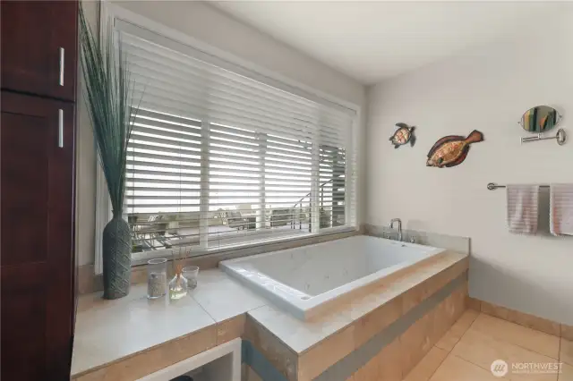 At the center of the space, a deep jetted soaking tub is perfectly positioned beneath a large picture window, offering a tranquil place to unwind while gazing out at the shimmering water and passing ferries. Whether its a sunrise reflection or evening light dancing on the surface, the view turns every bath into a serene experience.