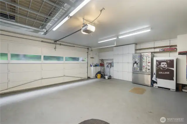 This spacious garage is more than just a place to park-it's a fully functional extension of the home with  a dedicated work area for projects and plenty of cabinents for storage.