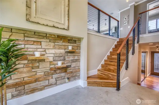 The entry way has a modern flare with concrete floors and a unique stone wall.