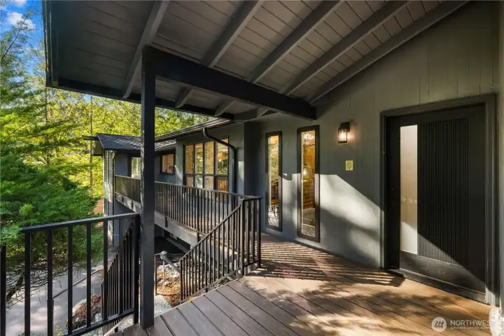 Covered front deck with new railings and architectural details offers a welcoming arrival and seamless indoor-outdoor flow.