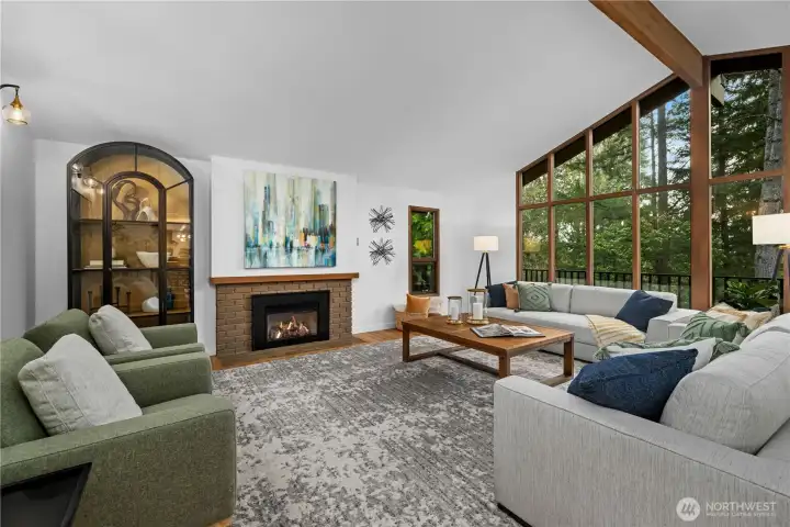 Open-concept living space featuring a fireplace, site-finished white oak floors, and expansive windows that create a seamless connection to the outdoors.