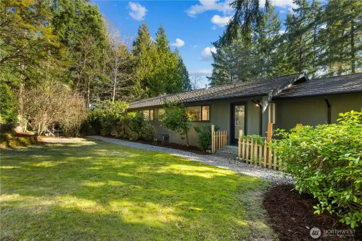 Private, sun-filled yard framed by mature evergreens, offering space to relax, play, and entertain.