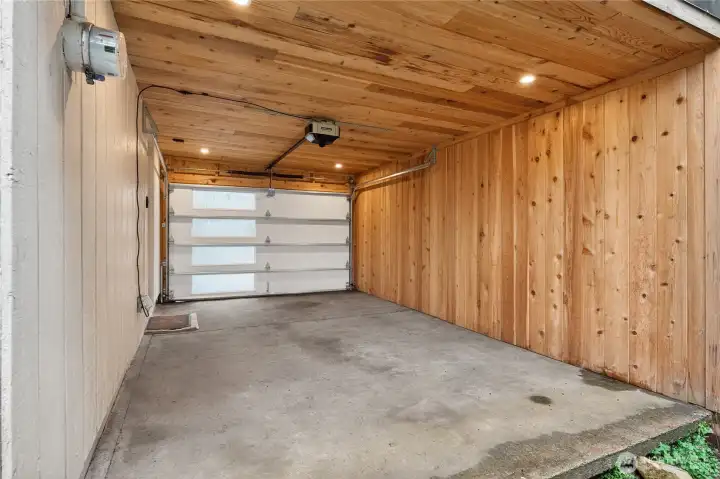 Covered carport with new garage door offers flexible use as protected parking or outdoor living area.