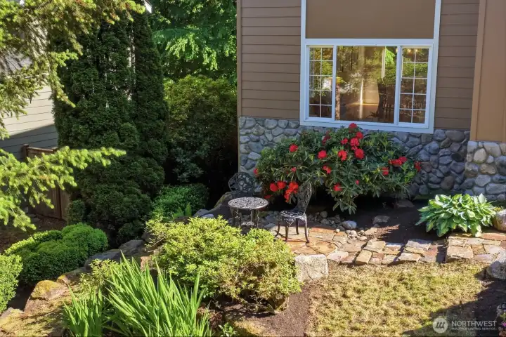 Inviting stone front patio framed by mature landscaping creates exceptional curb appeal.