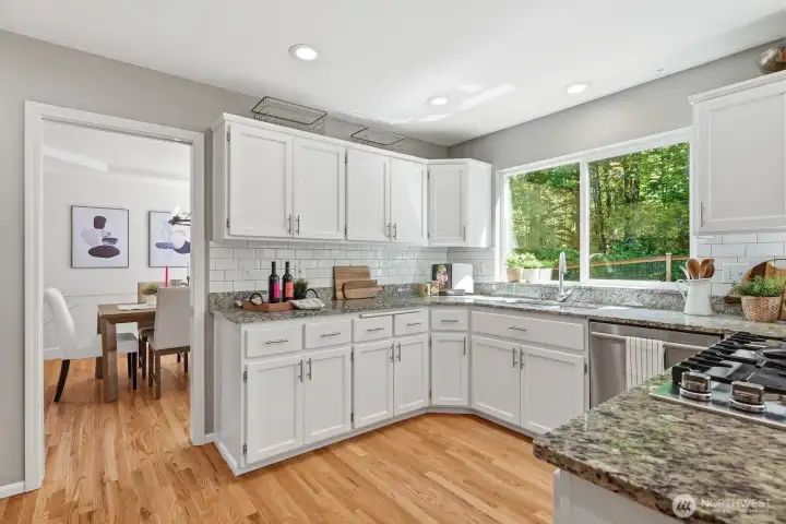 Seamless transition into the remodeled kitchen featuring backyard views and tranquil greenbelt scenery from the window.