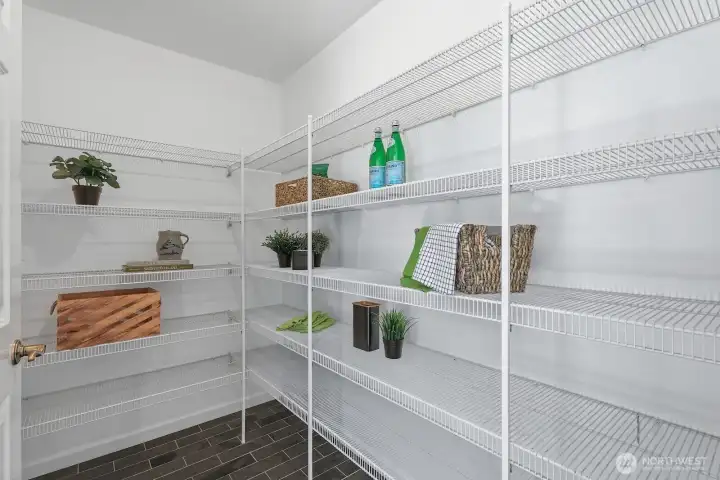 Oversized walk-in pantry featuring tile flooring and abundant wraparound shelving for exceptional storage and organization.