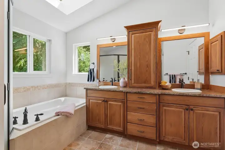 Luxurious 5-piece primary bath with vaulted ceilings, skylights, soaking tub, tiled shower and tub surround, double vanity, linen closet, and abundant storage.