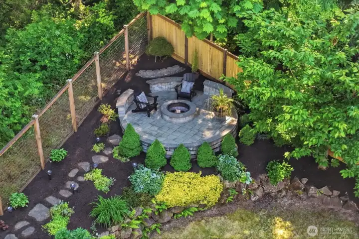 Elevated stone patio with built in fire pit and bench seating overlooks the backyard, greenbelt and Mt. Si, creating the perfect setting for relaxing evenings under the stars.