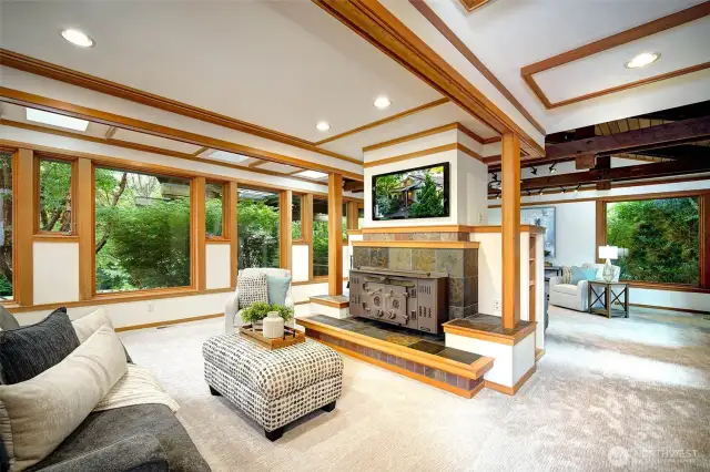 Spacious Family Room with wood beam details and wall of windows. Gather at the cozy fireplace!