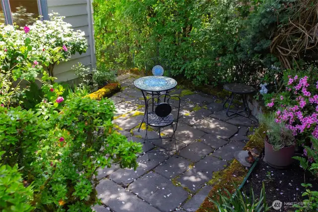 The charming patio, surrounded by flowers, is at the SW corner of the property.