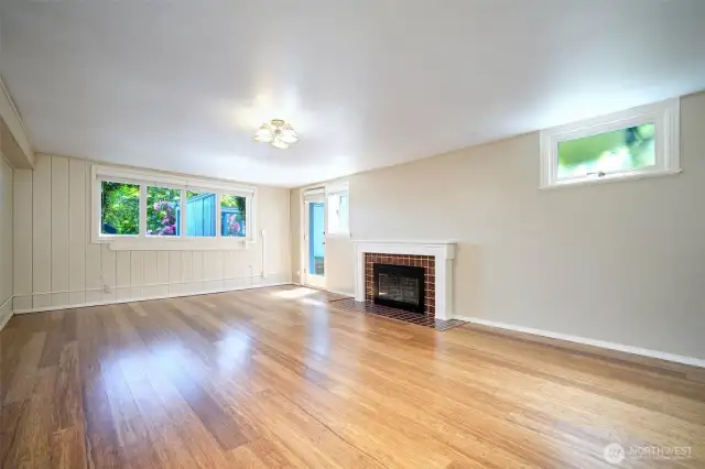 Lower level Family Room, with a cozy wood burning fireplace. The door leads to the south side of the home, as well as another private patio that faces Lake WA.
