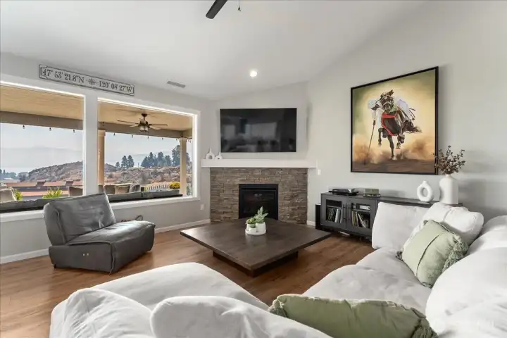 View of Living Room with fireplace and windows looking out over the outdoor living area with lake views.