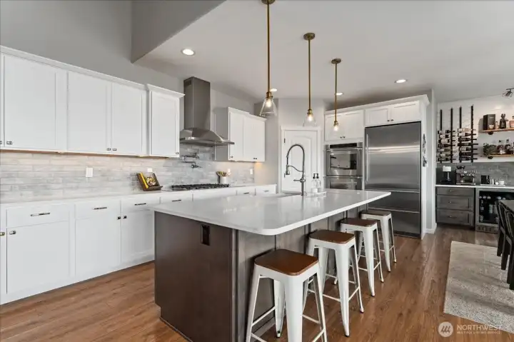 View of kitchen with quartz countertops and island with seating for four.