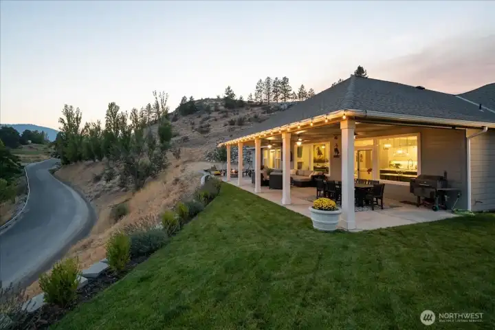 Exterior twilight view of outdoor living area with BBQ, dining, lounge area and fire pit.