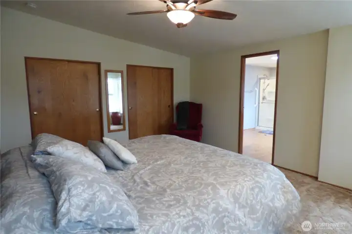 Primary bedroom with double closets, vaulted ceiling and fan.