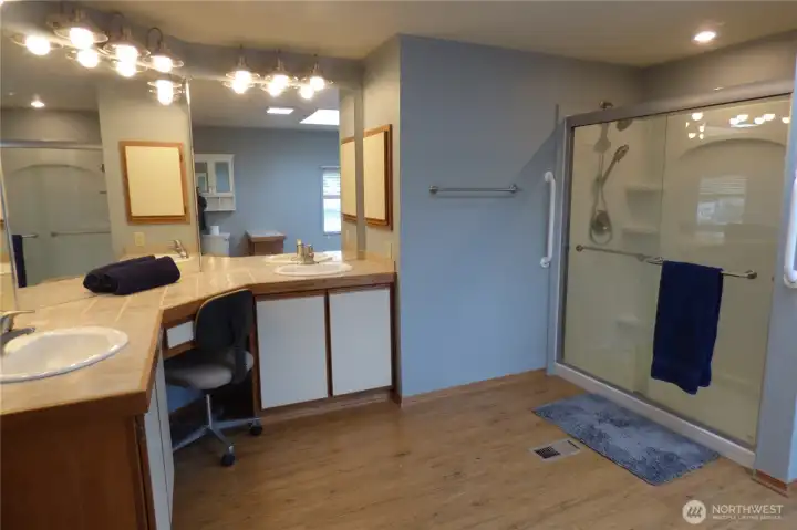 The other side of the primary bathroom with large shower, double sinks and a sit down counter.