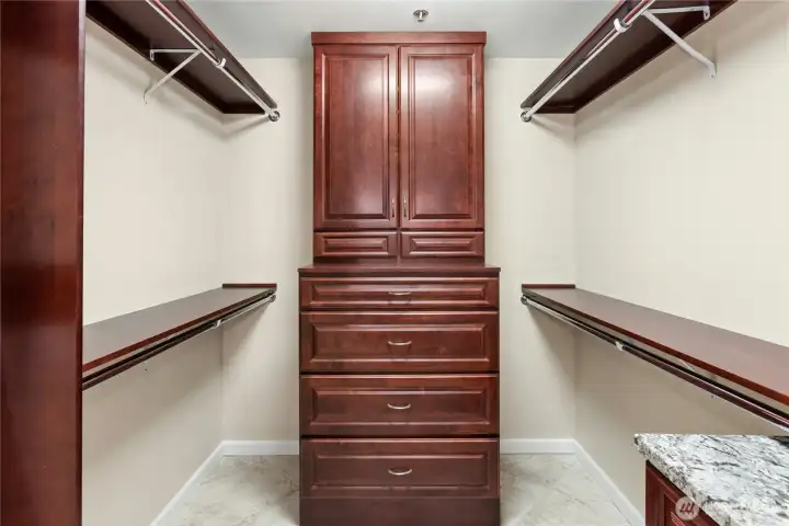 This remodeled walk-in closet in the primary suite has plenty of hanging space plus built-in cherry dressers to match the bath vanity.