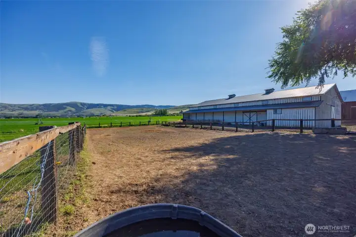 View toward the indoor arena and expansive outdoor riding arena, highlighting this premier equestrian setup designed for year-round use. Ideal for horse enthusiasts, training, events, or a private ranch lifestyle, with wide-open space, functional layout, and endless potential to create your dream equestrian property in Ellensburg.