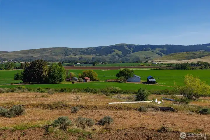 View looking south from the irrigation ditch back toward the homes and outbuildings, offering a different perspective of the property’s layout. This angle highlights the relationship between the agricultural infrastructure and the residential improvements, showcasing both functionality and rural lifestyle appeal.