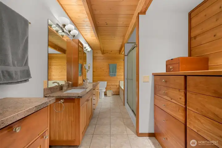 The 5 piece primary bathroom has granite counters, a jetted tub, and a custom built-in dresser.