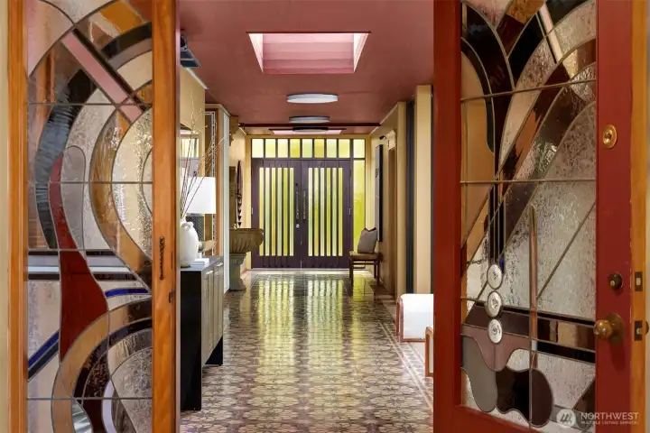 A striking hallway flows into the interior living through dramatic stained-glass double doors.