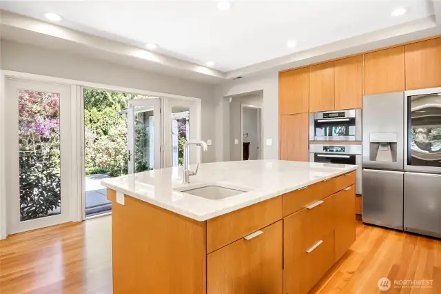 Abundant natural light pours in, highlighting the rich hardwood floors and creating a space where cooking becomes a true pleasure.