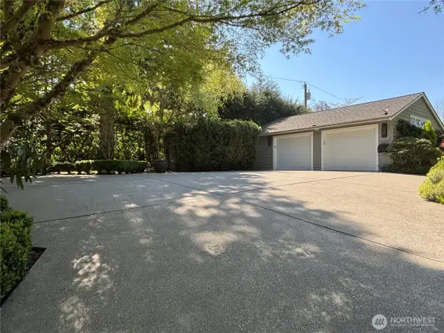 This generously sized motor court provides ample parking for guests, beautifully framed by lush trees and vibrant plantings, creating an inviting first impression.