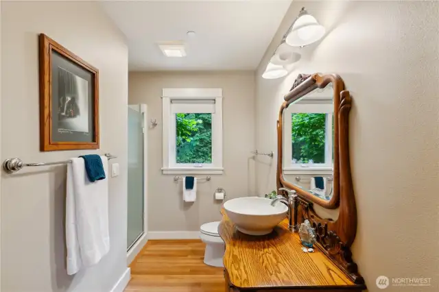 The 3/4 bathroom in the main level hallway has a solid oak custom vanity.