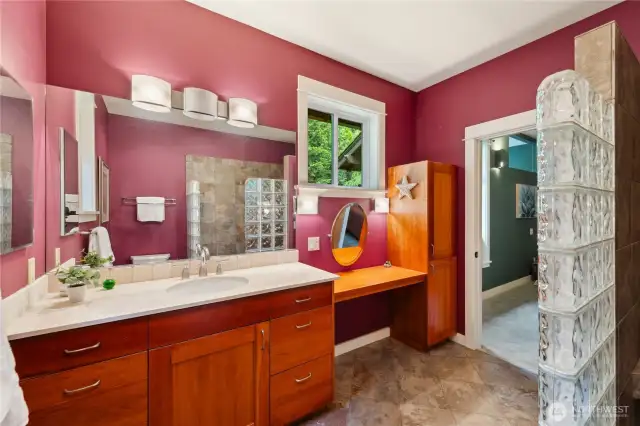 The main level primary bathroom. It has a walk-in tile shower and built-in solid wood makeup table.