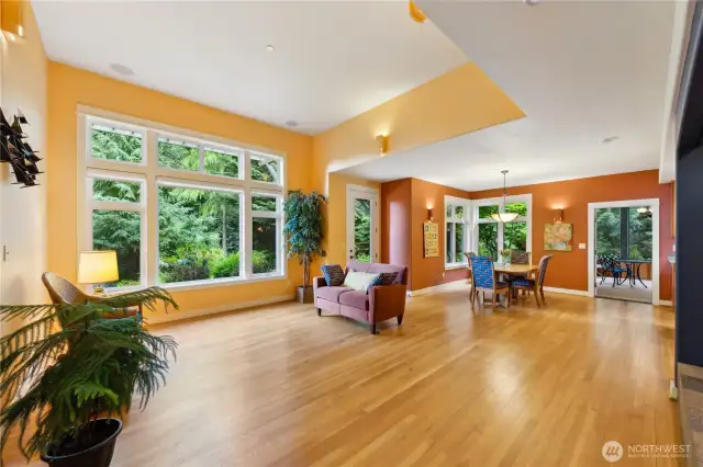Solid oak floors in the great room and most of the main level. White woodwork frames tall windows looking out onto mature landscaping.