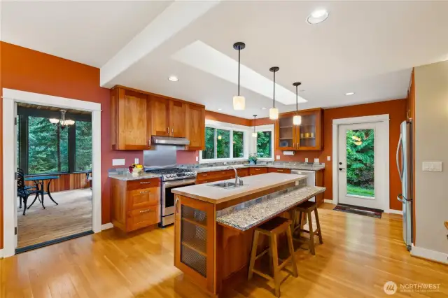 Granite breakfast bar in the kitchen is attached to the butcher block island, with prep sink. Glass display cabinets.
