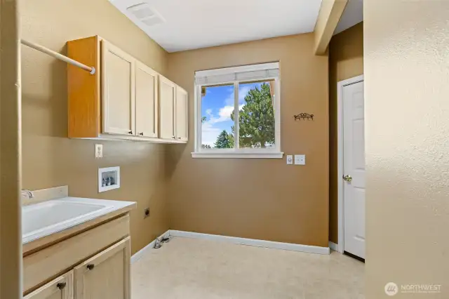 Laundry room with sink and storage and door leading to garage..