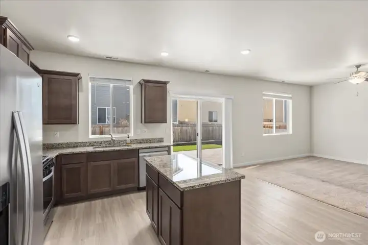 The kitchen features granite countertops, wood cabinetry with crown molding, a pantry with built-in shelving, and stainless steel appliances including a gas range, and a WiFi-enabled dishwasher. Carpet in living room replaced since photo taken.