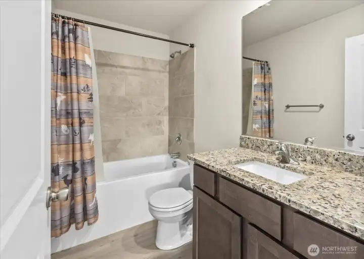 Full guest bath with tub and tiled shower and granite topped vanity.