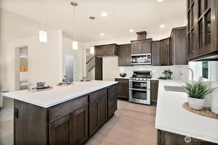 Quartz countertops with full tile backsplash and pendants.