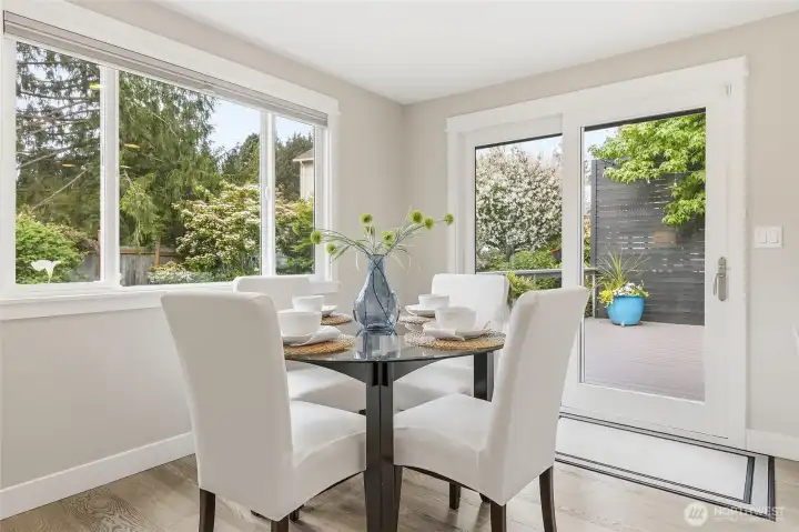 Bright Dining Area with Rich Hardwood Flooring, Expansive Windows, and Glass Door access to Big Private Deck and Fenced Backyard features Abundant Natural Light, Contemporary Finishes, and Seamless Indoor-Outdoor Flow Ideal for Everyday Dining, Backyard Barbeques, and Entertaining
