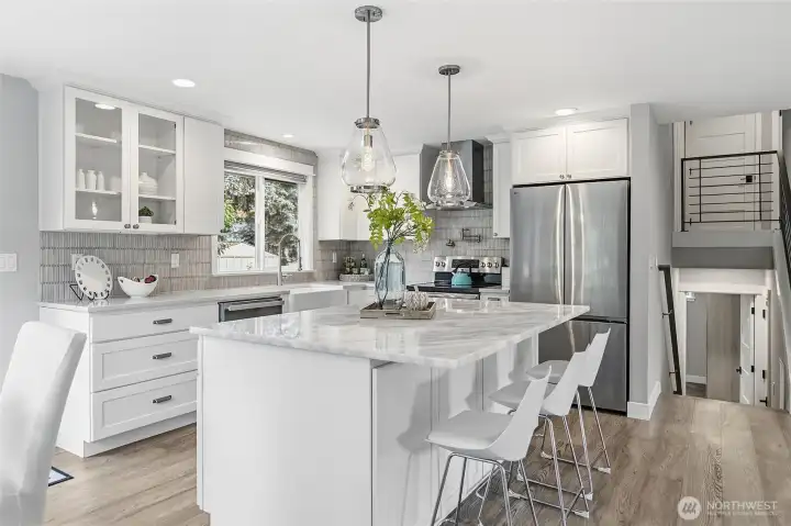 Beautifully Remodeled Kitchen featuring a Large Imported Marble Top Island with Bar Seating,Quartz Counters, Custom White Cabinetry, Designer Pendant Lighting,Tile Backsplash, Farmhouse Sink, and Stainless Steel Appliances including New Refrigerator. Also Plumbed for Future Gas Cooking.