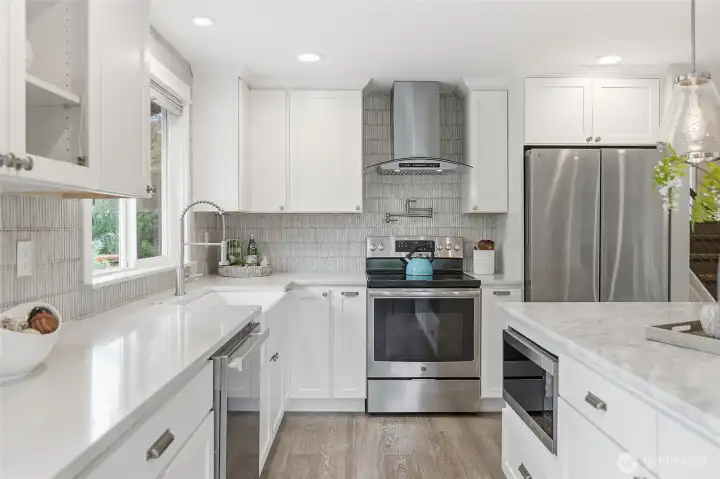 Beautifully Remodeled Kitchen featuring a Large Imported Marble Top Island with Bar Seating,Quartz Counters, Custom White Cabinetry, Designer Pendant Lighting,Tile Backsplash, Farmhouse Sink, and Stainless Steel Appliances including New Refrigerator. Also Plumbed for Future Gas Cooking.