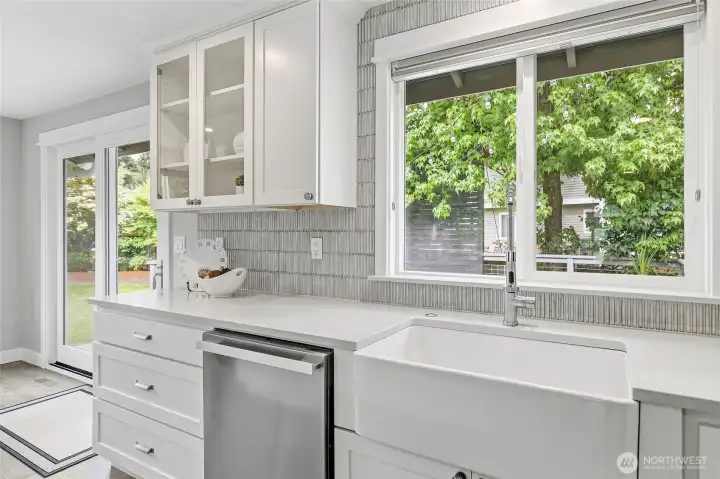 Beautifully Remodeled Kitchen featuring a Large Imported Marble Top Island with Bar Seating,Quartz Counters, Custom White Cabinetry, Designer Pendant Lighting,Tile Backsplash, Farmhouse Sink, and Stainless Steel Appliances including New Refrigerator. Also Plumbed for Future Gas Cooking.