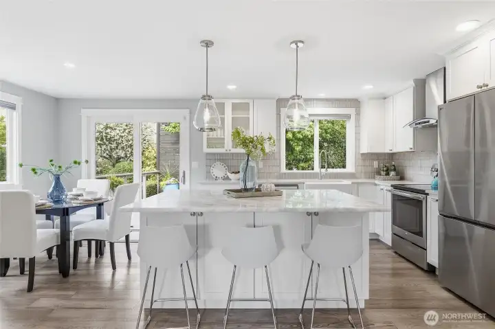 Beautifully Remodeled Kitchen featuring a Large Imported Marble Top Island with Bar Seating,Quartz Counters, Custom White Cabinetry, Designer Pendant Lighting,Tile Backsplash, Farmhouse Sink, and Stainless Steel Appliances including New Refrigerator. Also Plumbed for Future Gas Cooking.