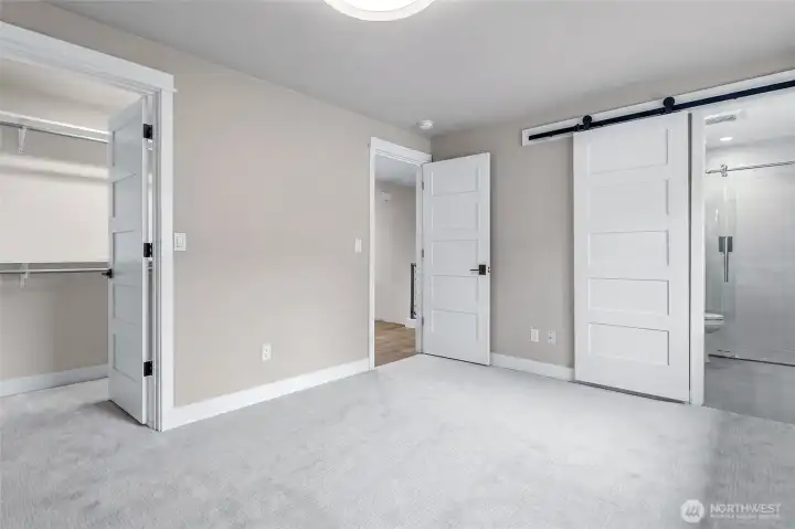Spacious Primary Suite featuring New Plush Carpeting, Contemporary Neutral Tones, and Big Windows streaming Abundant Natural Light. Stylish Modern Barn Door opens to the Ensuite Bath, while the Walk-in Closet provides Generous Wardrobe Space. Crisp White Trim, Updated Paneled Doors, and a Bright, Airy Layout create a Comfortable and Inviting Retreat.