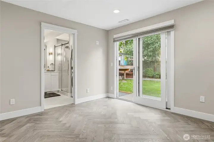 Family Room with Access to Backyard and Built-in Storage Closet can be used as a 2nd Primary Bedroom with New En-suite Bath featuring a Raised Mirrored Vanity with Quartz Counters, Double Sinks, Designer Lighting, Heated Tile Floors, and Stacked Washer and Dryer.
